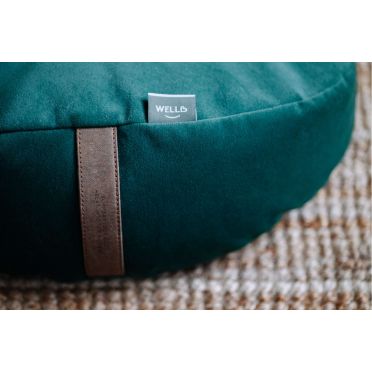 Zbliżenie na zieloną welurową poduszkę do jogi i medytacji z metką WELLB i uchwytem.